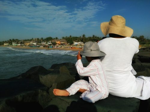 parent and child wearing sun hats looking at the beach in pondicherry